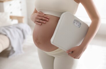 Young pregnant woman with scales at home, closeup