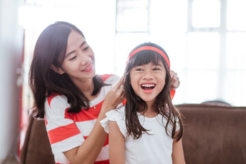 mom tying red ribbon on her daughter's forehead