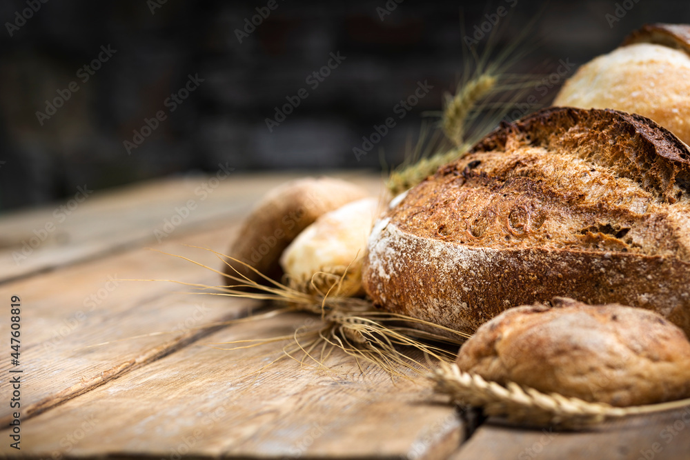 Poster assortment of different types of bread from rye and wheat flour on a wooden table in a bakery. сopy 