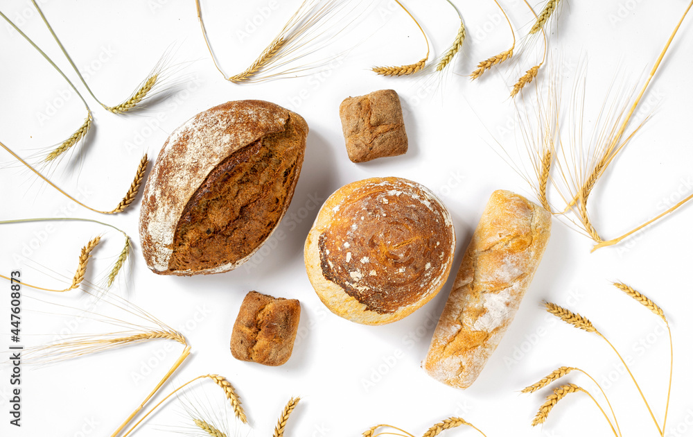 Poster bakery. set of freshly baked crispy bread and buns with ears of wheat on white background top view, 