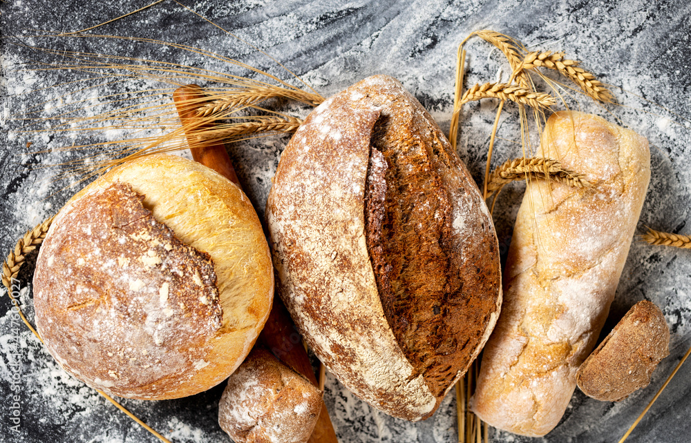 Poster bakery background. freshly baked crispy bread and buns with ears of wheat top view