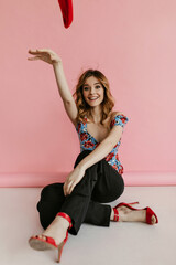 Joyful woman with curly blond haired in blue top and black trousers smiling on isolated background. Smiling girl in stylish girl posing..