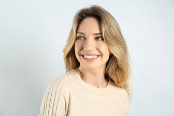 Obraz premium Portrait of happy young woman with beautiful blonde hair and charming smile on light background