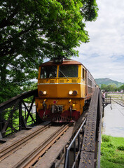 The diesel-electric locomotive of the local train is driving through the old steel bridge carefully.