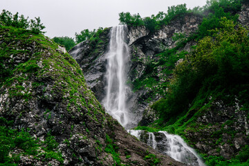 Beautiful mountain waterfall among trees, summer natural background