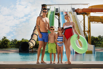 Happy family with inflatable ring near pool in water park