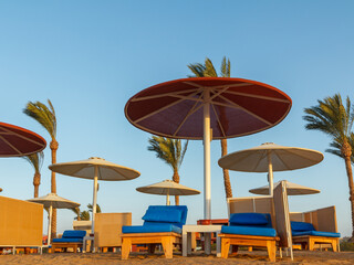 Beach with umbrellas and sunbeds against the blue sky.