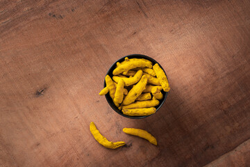 dry organic Tumeric fingers or Curcuma or halkund in a wooden bowl on a wooden dark theme