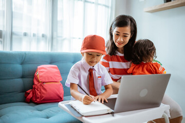 asian mother helping her daughter to study during online class meeting at home