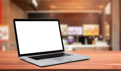 Laptop or notebook with blank screen on wood table in blurry background with fast food restaurant or coffee shop ,nature orange bokeh and sunlight in morning.