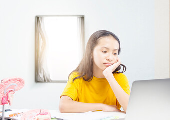 Asian little girl with laptop attending to online school class at home