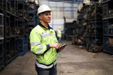 Worker or Engineer work in factory and using tablet for checking stock and inspection in machine spare part engine warehouse