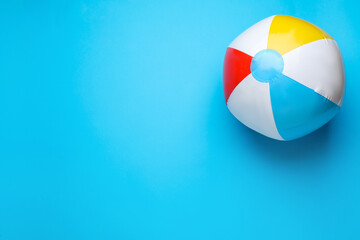 Bright beach ball on light blue background, top view. Space for text