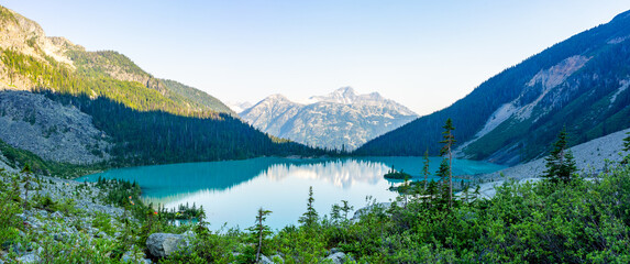 Emerald Upper Joffre Lake panorama with a mountain backdrop and tents on the shoreline in British Columbia, Canada