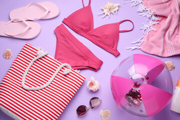Flat lay composition with beach ball and other accessories on violet background