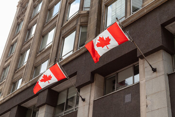 Canadian flags waving in the wind, attached to building in downtown of Ottawa city in Canada.