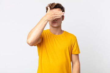 young handsome man covering eyes with one hand feeling scared or anxious, wondering or blindly...