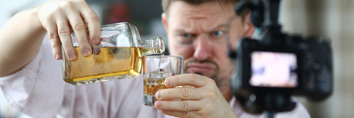 Man with hematoma under his eye pouring alcohol and taking video camera