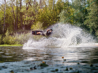 An athlete performs a wakeboard trick with water splashes.