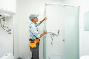 Plumber installing a shower cabin in bathroom