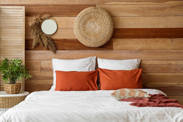 Comfortable bed near wooden wall