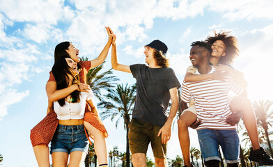 Group of happy multiracial friends celebrating outdoors with back sunlight - Multiethnic people...