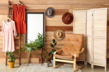 Modern armchair and folding screen near wooden wall