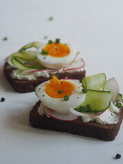 Healthy natural summer food.Sandwiches with whole grain bread, cucumber, radish and boiled egg on a white background.
