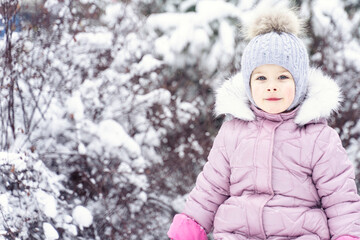 portrait of a cute caucasian girl in warm clothes in a snowy park