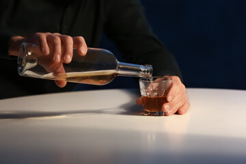 Senior man pouring drink in glass in kitchen at night, closeup