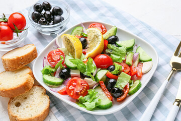 Plate with tasty Greek salad and bread on light background, closeup