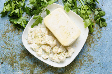 Plate with tasty feta cheese and parsley on color background
