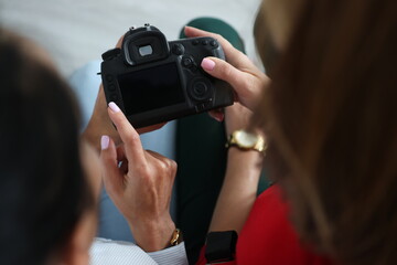 Two women hold camera in their hands and press buttons