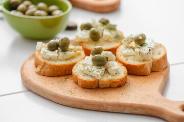 Sandwiches with tasty feta cheese and olives on light wooden table, closeup