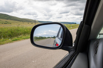 Fototapeta na wymiar Car mirror and highway view, black car and nature landscape