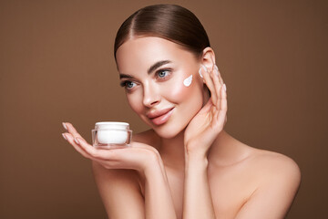 Beauty woman applying cream on her face. Young woman with clean fresh skin. Model with a jar of...