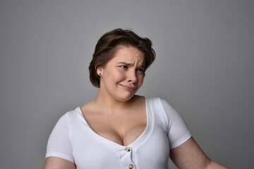 Close up portrait of young plus sized woman with short brunette hair,  wearing a white shirt, with...