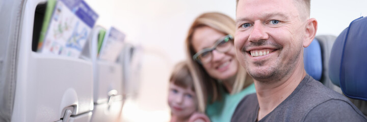 Smiling parents with child are sitting in aircraft cabin