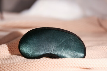 Stylish sleeping mask on bed in room