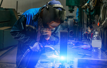 Welder working with electrode at semi-automatic arc welding.