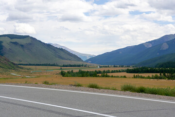 Naklejka premium mountains against the background of clouds and the road stretching into the distance