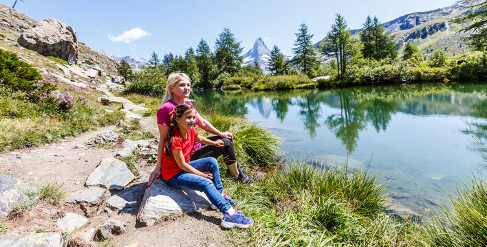Happy hiker woman and girl at mountains lake