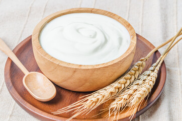 Greek yogurt in a wooden bowl and dry barley.
