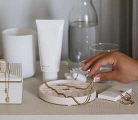 Woman's hand picking up jewelry on bedside table