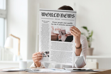 Young woman reading newspaper at home