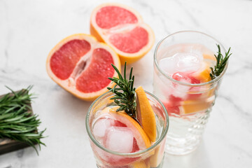 Glasses of tasty grapefruit cocktail with rosemary on light background, closeup