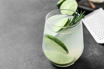 Glass of tasty lime cocktail with rosemary on dark background, closeup