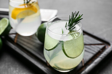 Glass of tasty lime cocktail with rosemary on dark background, closeup