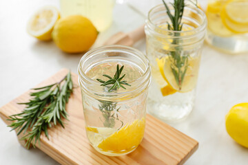 Glasses of tasty lemonade with rosemary on light background