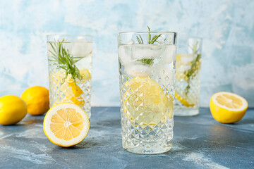 Glasses of tasty lemonade with rosemary on color background